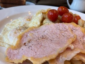 A perfect breakfast of two eggs over easy, breakfast potatoes, and peameal bacon
